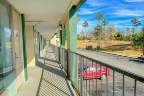 A corridor with a balcony overlooking a parking area and trees. - Super Inn And Suites (Milledgeville)