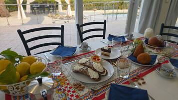 Ein gedeckter Tisch mit Speisen, einer Kaffeekanne und Blick ins Freie.