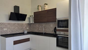 A modern kitchen with a flat-screen TV, built-in oven, and a microwave.