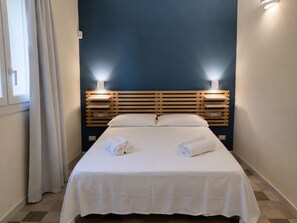 Habitación de hotel con cama, dos lámparas de noche y una ventana con cortinas.