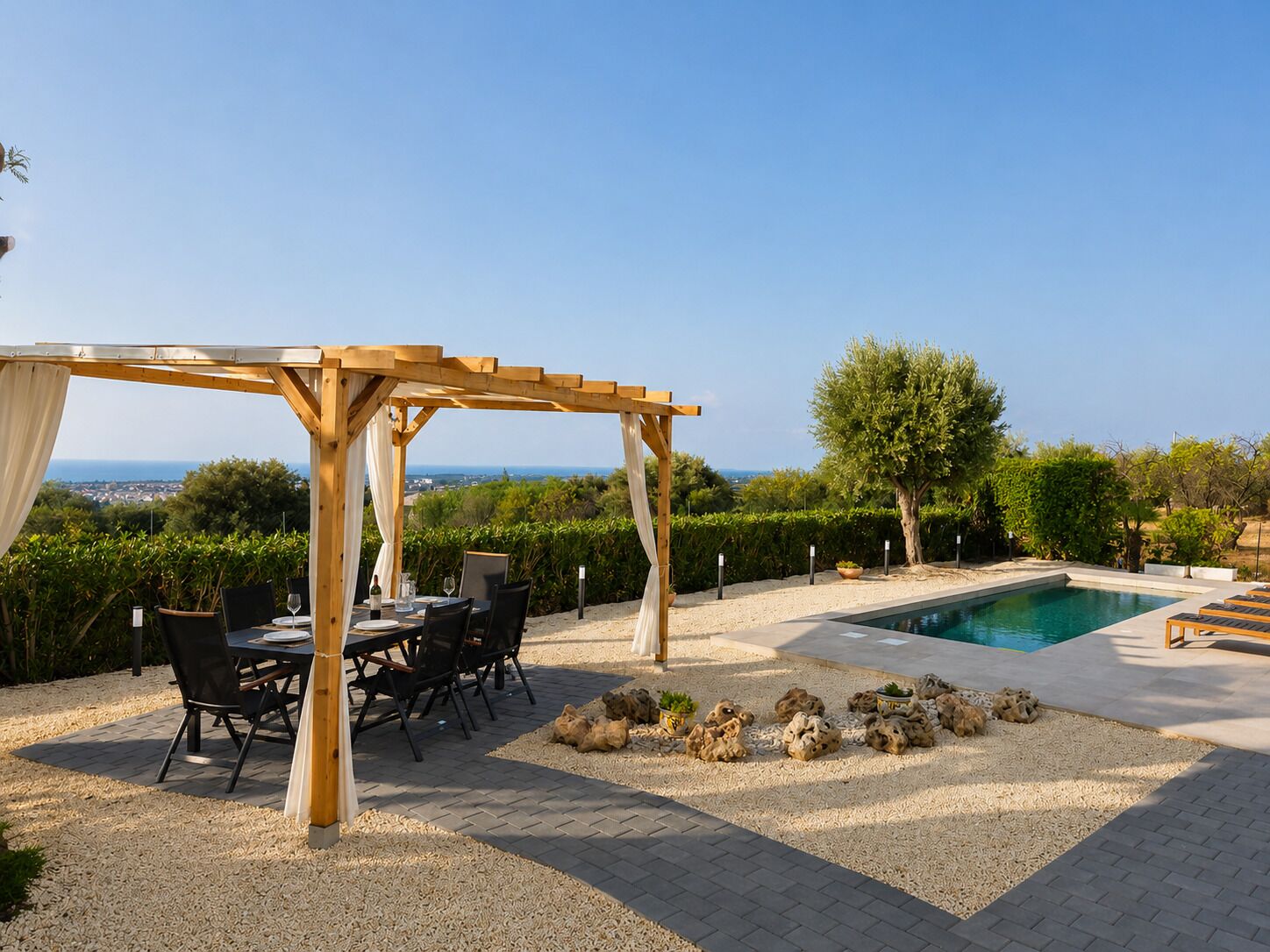 Un espace extérieur abrité, aménagé pour les repas, avec une piscine et une vue sur la mer.