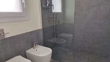 Ein Badezimmer mit Toilette, Bidet und einer Duschkabine.