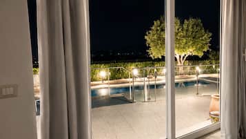 A room with a large sliding glass door leading to an outdoor swimming pool area at night.