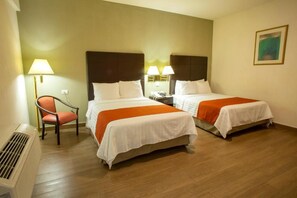 Habitación de hotel con dos camas, una silla, una lámpara y un cuadro en la pared.