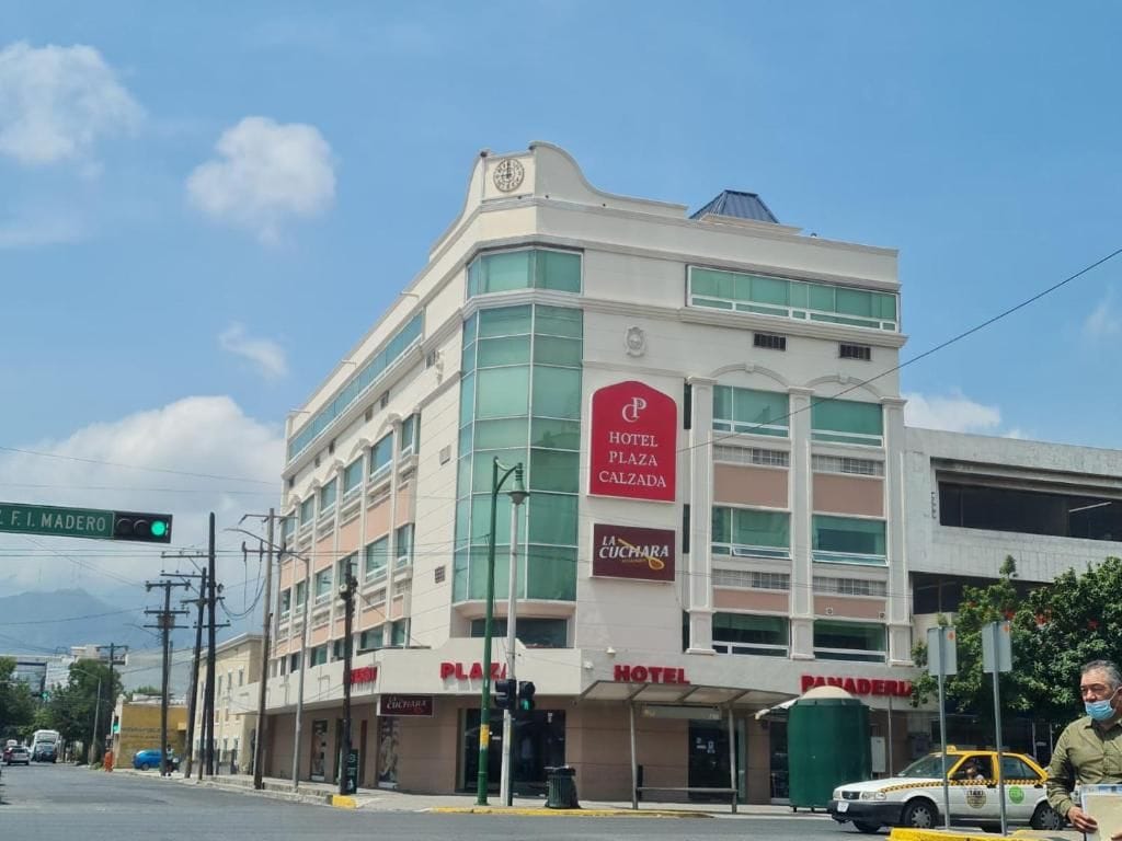 Un hotel con un llamativo letrero que dice 'Hotel Plaza Calzada', un restaurante 'La Cucumara' y una entrada 'Plaza'.