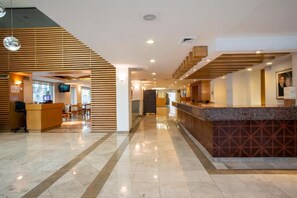 Un'accogliente hall dell'hotel con reception, area salotto e una scala.