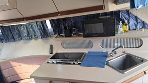 A compact kitchenette with a microwave, sink, and stove. - The Pink Lady Yacht - Beautiful Providence Marina (Providence)