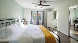 Ein Schlafzimmer mit einem Bett, einem Schreibtisch und einem Deckenventilator.