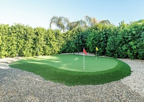 A well-maintained golf course with a putting green, two flags, and a dense hedge in the background. - Stylish 3-Bedroom Indio Retreat with Pool, A/C, and Modern Comforts (Las Vegas)