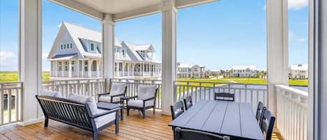 A covered outdoor deck with a wooden floor, a table, and chairs.
