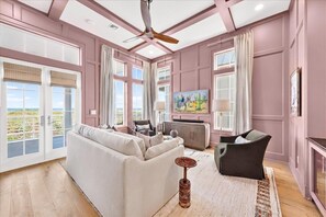 Ein Wohnzimmer mit einer Couch, Sesseln, einem Deckenventilator und einem Gemälde an der Wand.