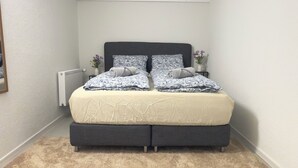 A bedroom with a bed, a radiator, and a carpet.