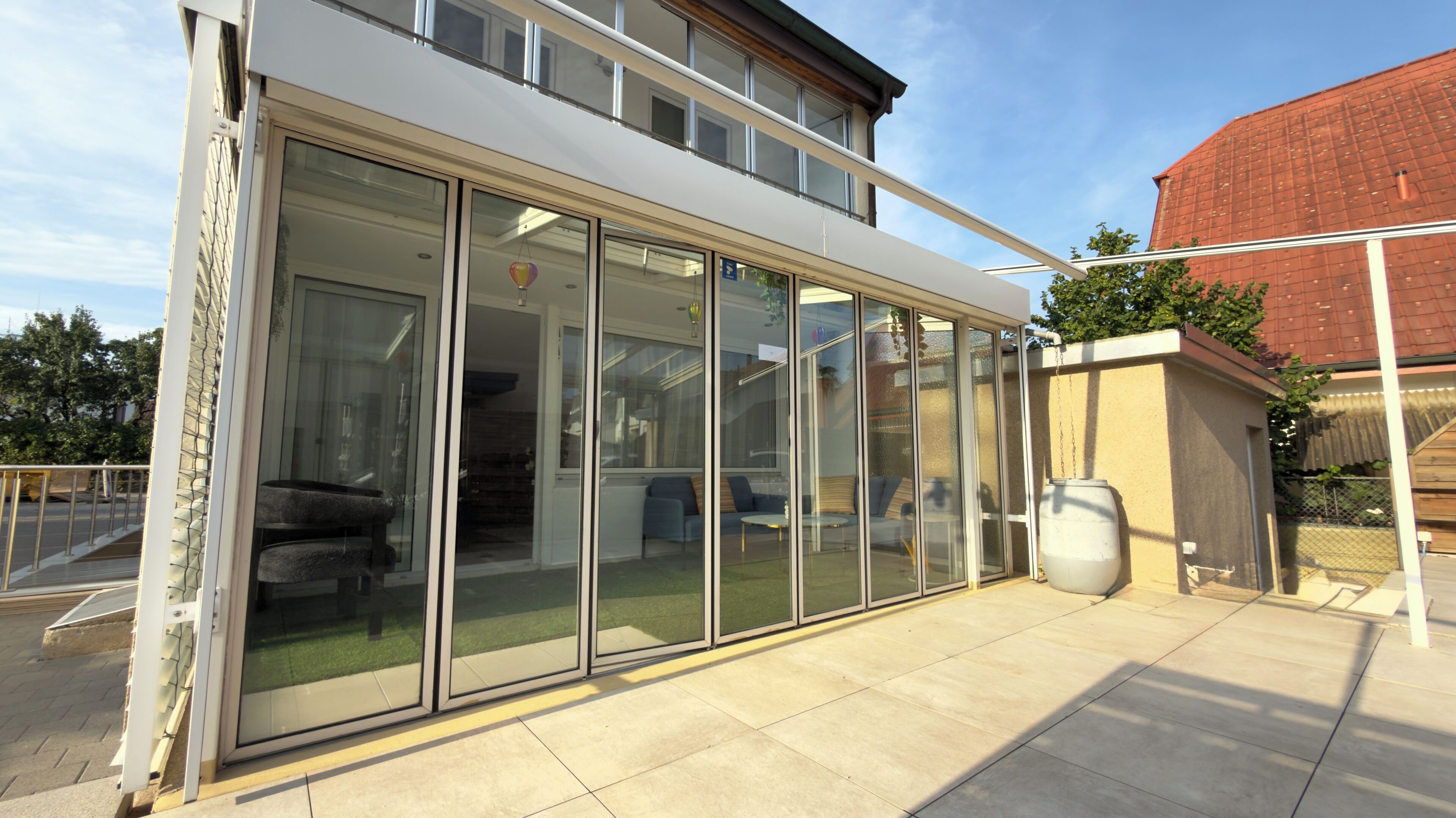 A modern house with a glass-enclosed patio, a large window, and a brick wall.