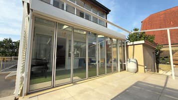 A modern house with a glass-enclosed patio, a large window, and a brick wall.