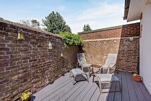 A wooden deck with outdoor furniture, a brick wall, and a lantern. - Host & Stay | The Coach House (Worthing)