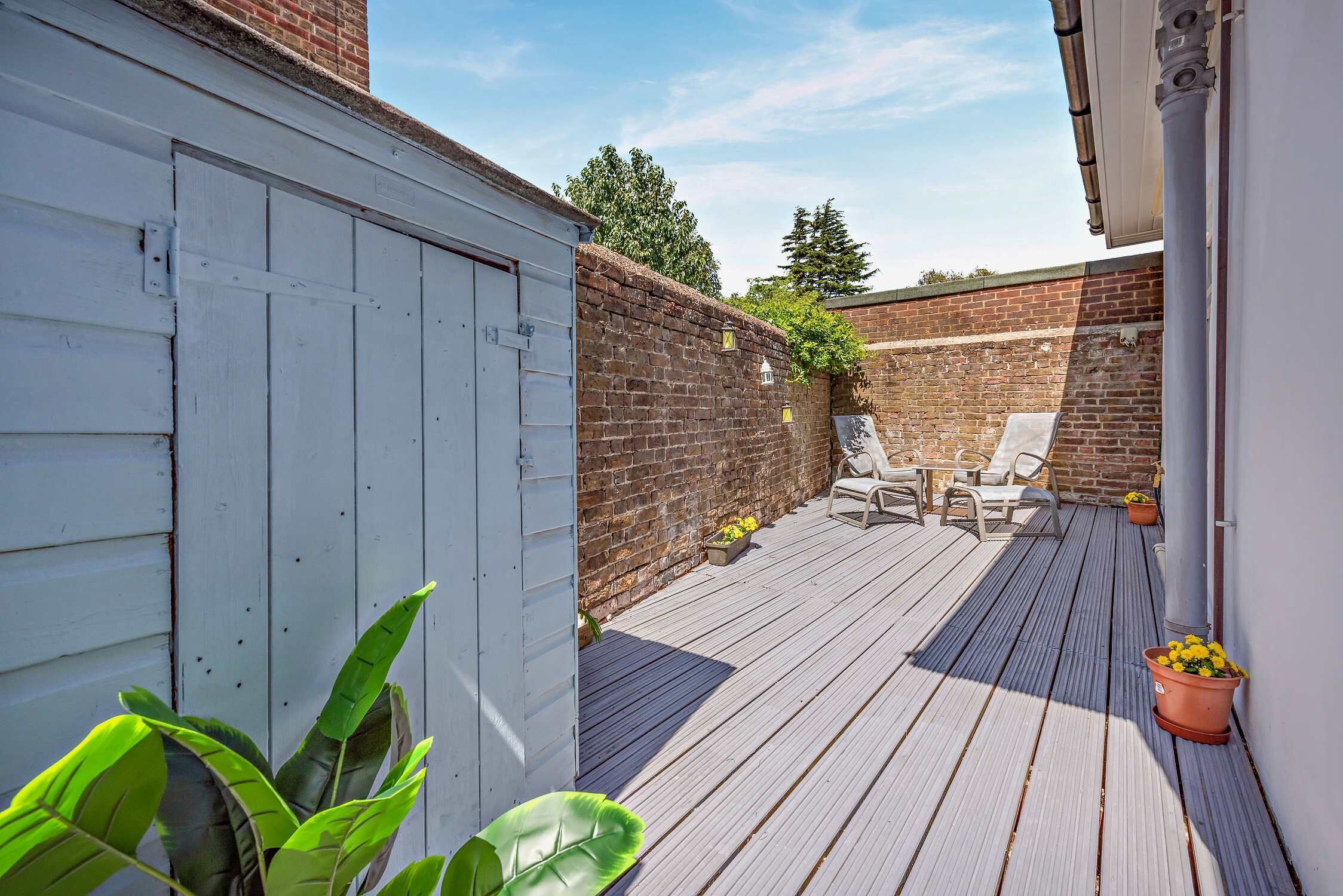 A wooden deck with outdoor seating and a brick wall.