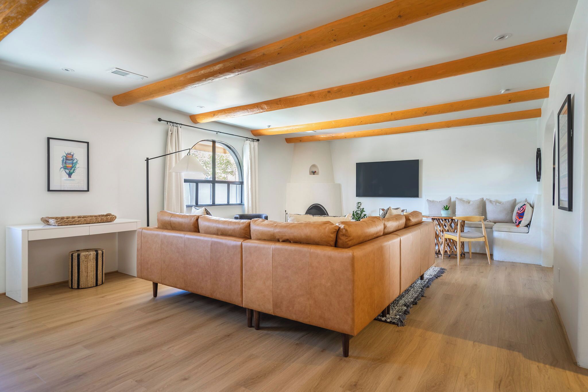 A spacious living area with a large sofa, a desk, and a television.