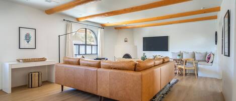 A spacious living area with a large sofa, a desk, and a television.