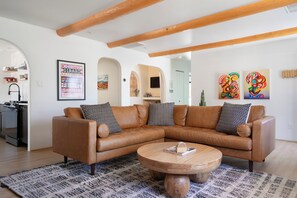 Ein Wohnzimmer mit einem braunen Ledersofa, einem runden Couchtisch aus Holz und einem gemusterten Teppich.