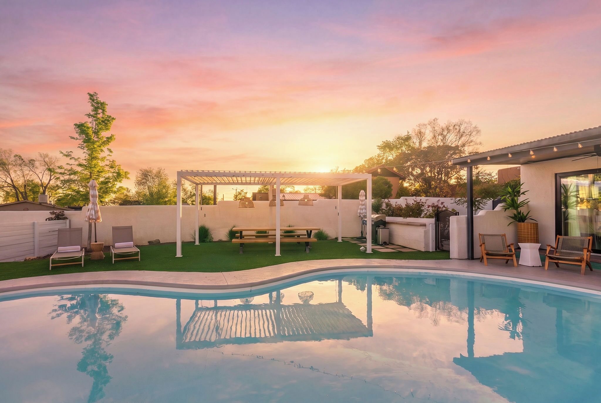 Un patio trasero con piscina, un área de patio techada y mobiliario exterior.