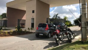 Un estacionamiento con coches y motocicletas, un edificio de techo plano y un cielo despejado.