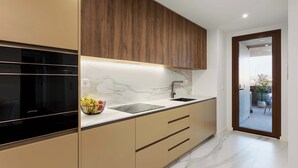A modern kitchen with a marble countertop, wooden cabinets, and a black stove. - Private Heated Pool & Dom Luis Views by HostWise (Vila Nova de Gaia)