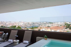 Ein Balkon mit Pool, Liegestühlen und Blick auf eine Stadtlandschaft.