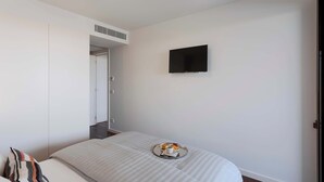 A bedroom with a bed, a flat-screen TV mounted on the wall, and a tray with a cup and pastries on the bed. - Private Heated Pool & Dom Luis Views by HostWise (Vila Nova de Gaia)