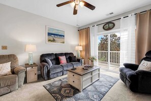 Ein Wohnzimmer mit einer Couch, Sesseln, einem Couchtisch und einem Deckenventilator.