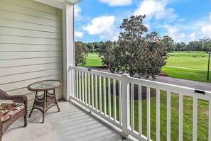 A porch with a white railing, a wicker table, and two wicker chairs. - World Tour Fairway Condo • Pool • 10 Min to Beach (Myrtle Beach)