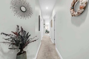 A hallway with a decorative mirror, a plant, and a wall-mounted wreath. - World Tour Fairway Condo • Pool • 10 Min to Beach (Myrtle Beach)