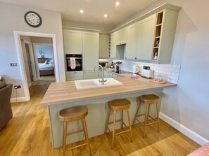 Cocina moderna con una isla central, taburetes de madera y armarios de tonos claros.