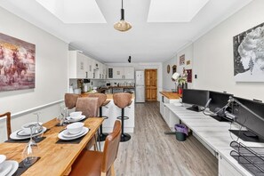 Eine moderne Küche mit weißen Schränken, einem Holzespeisetisch mit Stühlen und einer Kücheninsel mit Spüle und Arbeitsfläche.