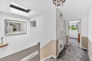 Ein Flur mit Oberlicht, Spiegel und einer Tür zu einem weiteren Zimmer.