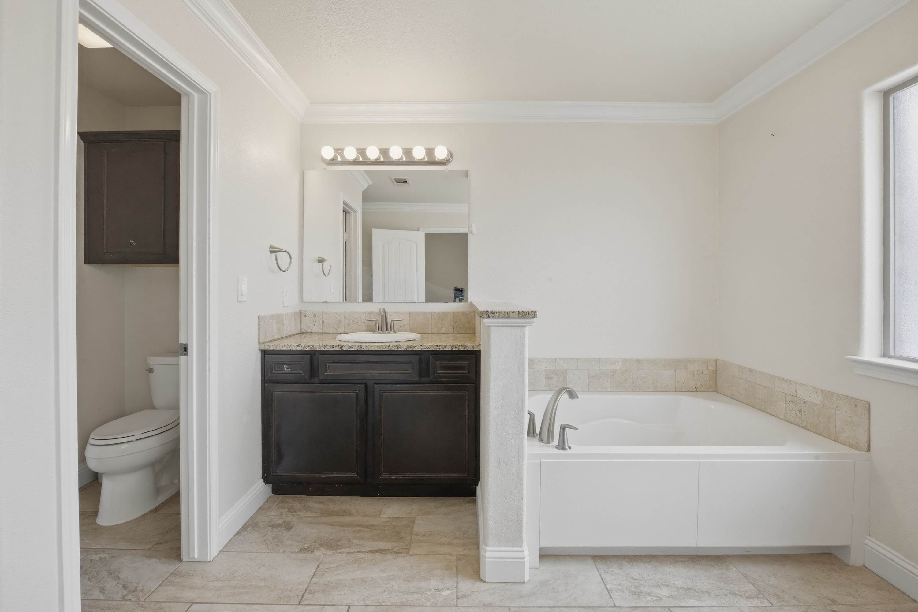 A bathroom with a toilet, sink, vanity, and bathtub.