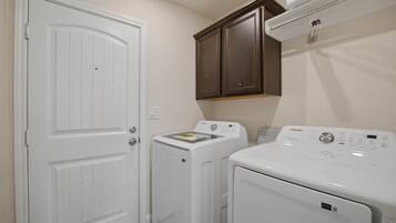 A laundry room with a white door, a washing machine, a dryer, and a cabinet above the dryer.