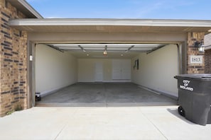 Eine Garage mit freiem Zugang, einer Mülltonne mit dem Aufdruck 'City of Midland' und einer Ziegelwand auf der linken Seite.