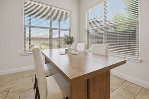 Et mødelokale med et langt træbord, hvide stole og store vinduer med persienner.