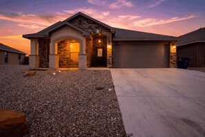A residential house with a driveway, garage, and a stone facade. - Acomm Corporate Housing - 4 Bedroom 2 Bathroom Deluxe - Perfect for Teams (Midland)