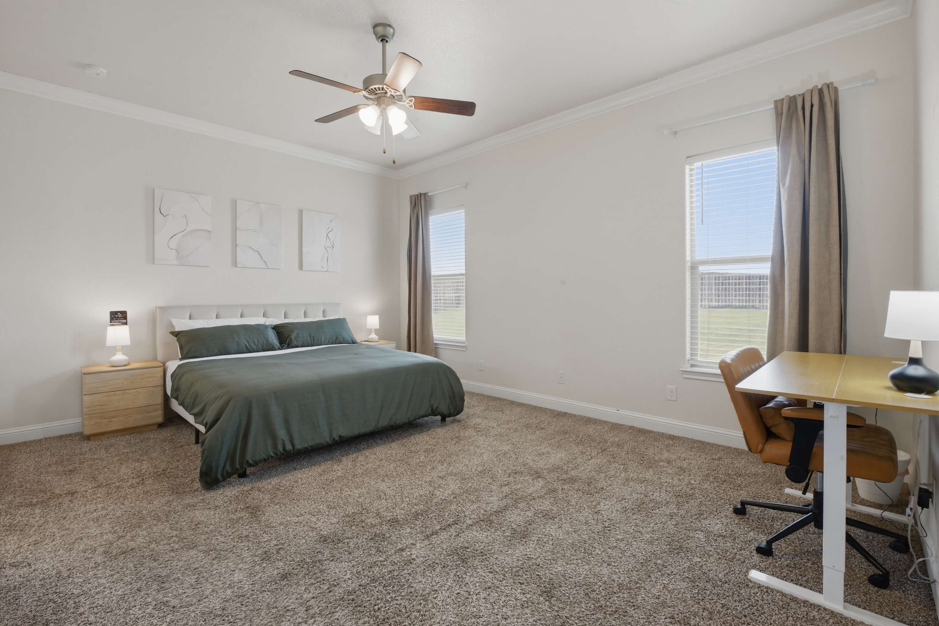 Ein Schlafzimmer mit Bett, Schreibtisch, Stuhl, Deckenventilator und Wandbildern.