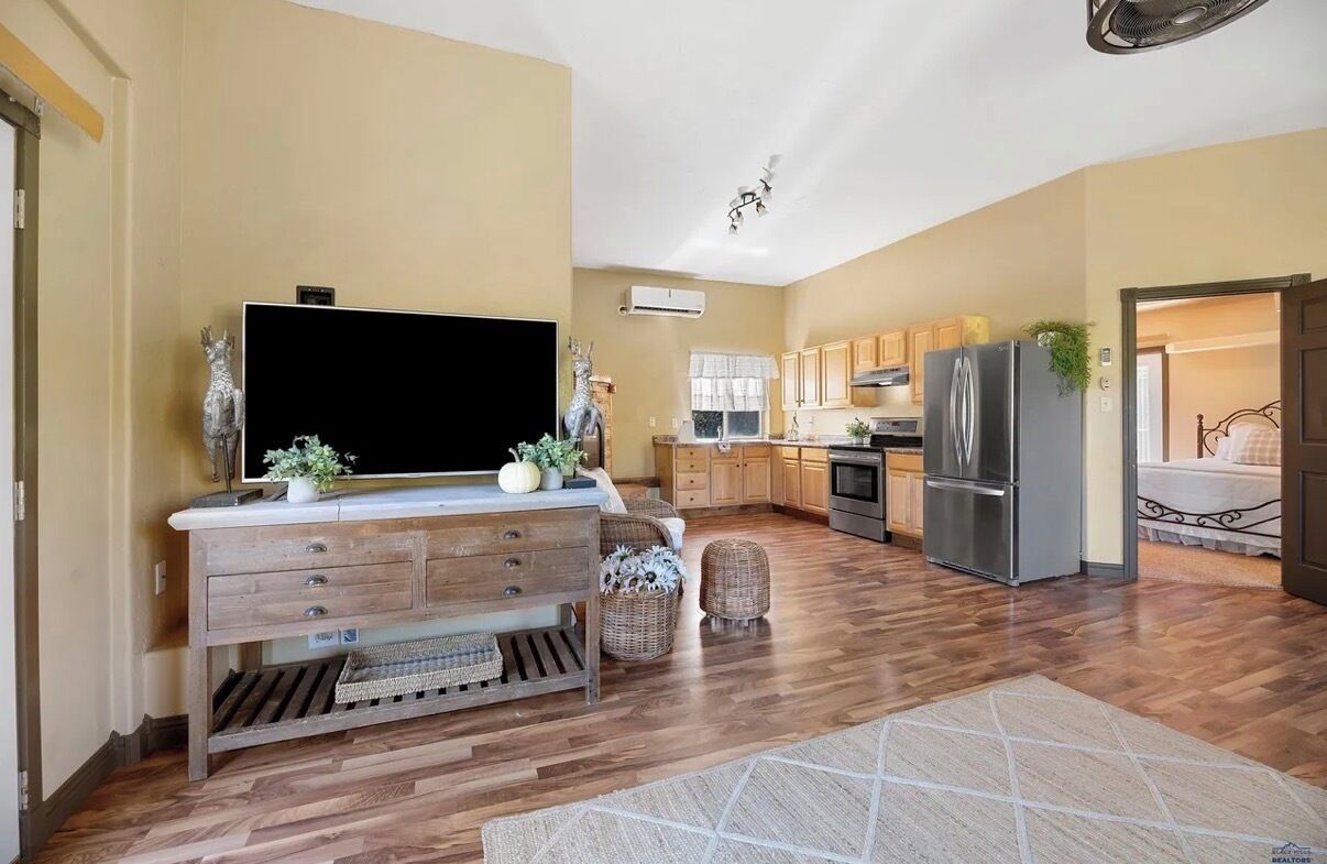 Une cuisine moderne avec des meubles en bois, un grand réfrigérateur et un téléviseur à écran plat posé sur une console en bois.