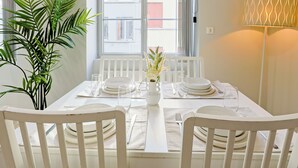 Una tavola apparecchiata con piatti bianchi, bicchieri e posate, un vaso con fiori e una pianta in vaso.