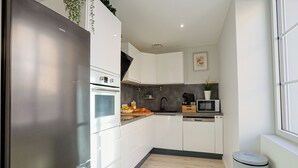 Una cucina moderna con mobili bianchi, frigorifero in acciaio inossidabile, forno integrato, microonde e lavastoviglie.