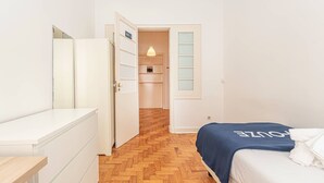 Hotellihuone, jossa on sänky, lipasto, peili ja ovi, joka johtaa kylpyhuoneeseen.