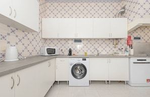 A compact kitchen with a washing machine, microwave, and a coffee maker. - HOUZE Historical Lisbon, flat with private patio (Lisboa)