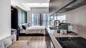A compact hotel room with a kitchenette, a bed with a view of the city, and a small seating area. - Pied A Terre With Roof Pool (Miami)