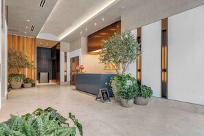 Eine moderne Hotellobby mit einer Rezeption, Topfpflanzen und einem Schild.