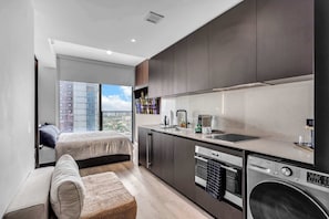 A modern apartment with a kitchenette, a bed, and a view of a cityscape. - Pied A Terre With Roof Pool (Miami)
