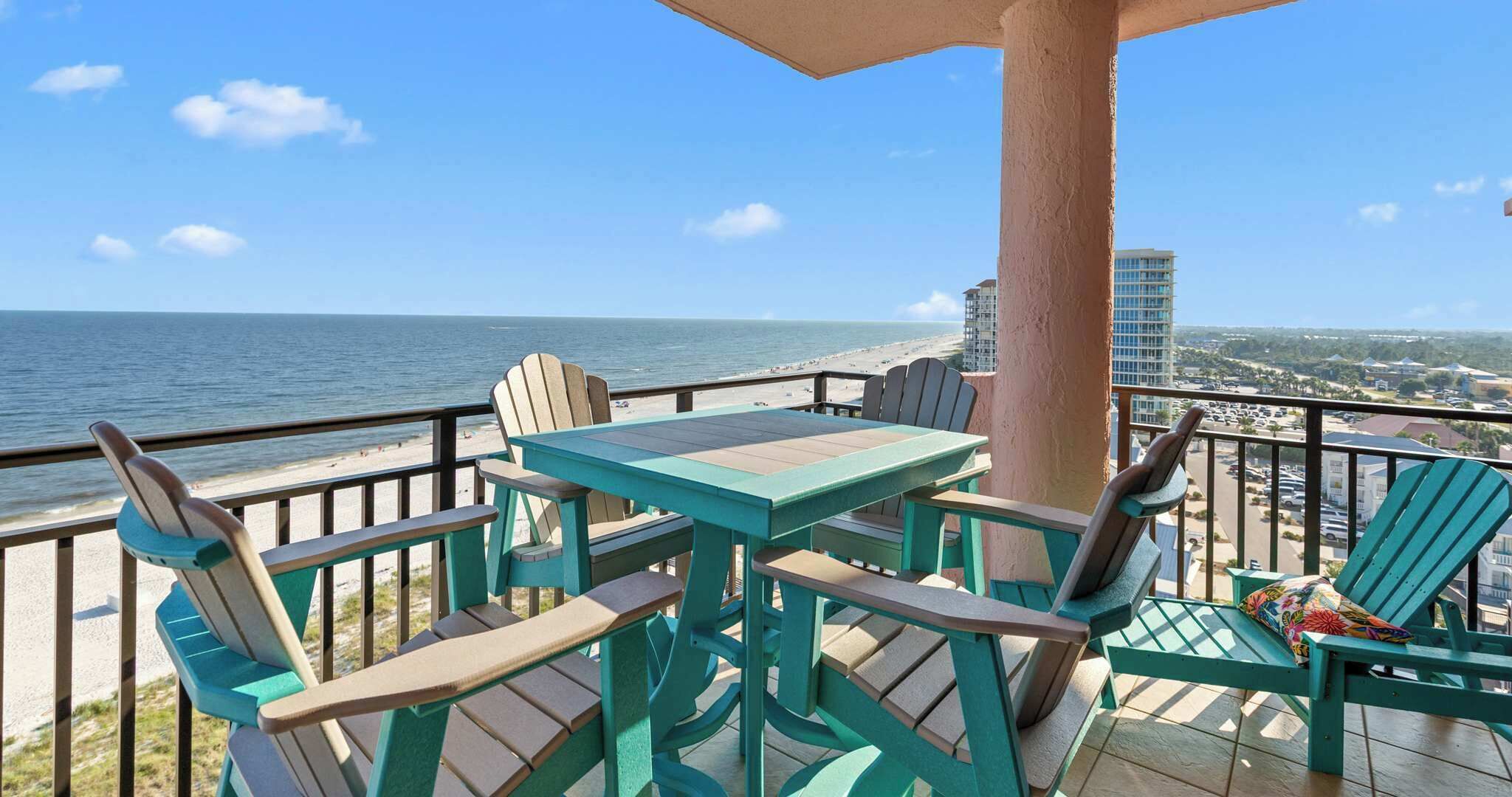 Un balcon avec une table et des chaises donnant sur une plage et offrant une vue sur la ville.