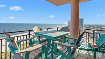 Un balcon avec une table et des chaises donnant sur une plage et offrant une vue sur la ville.